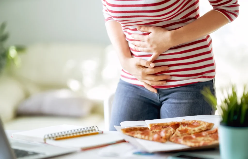 Mujer joven con retortijones después de comer alimentos grasosos - clinica de endoscopia avanzada